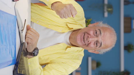 Vertical-video-of-Home-office-worker-old-man-getting-good-news-from-camera.